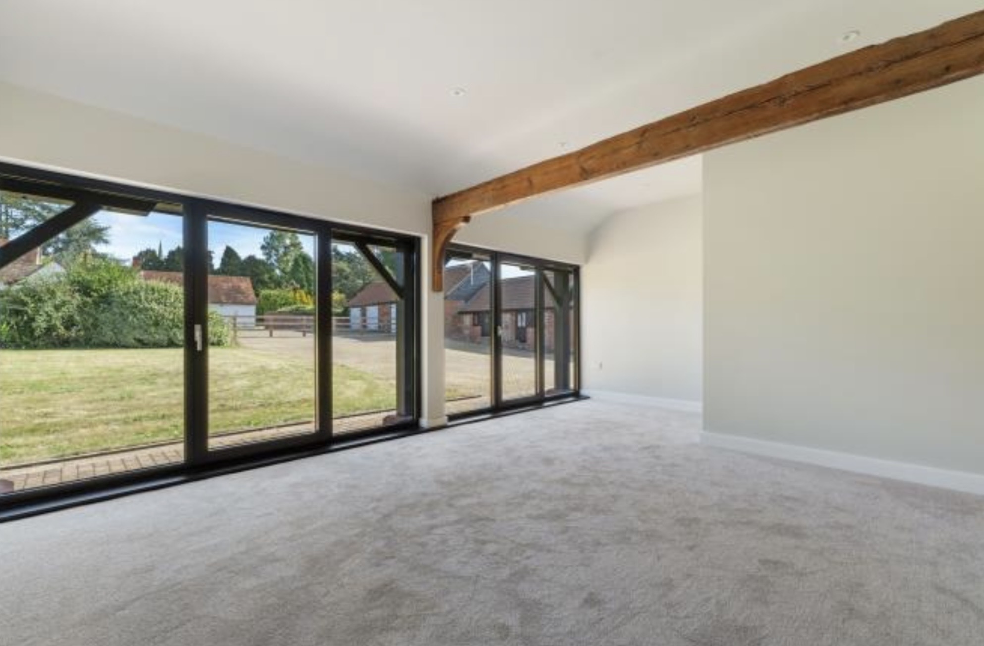 Thaxted barn conversion lounge with exposed oak beam and full-height glazing